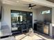 Inviting covered outdoor kitchen with a built-in BBQ and comfortable lounge seating on travertine tiles at 8250 Velda Trl, Sarasota, FL 34241