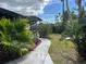 Landscaped backyard with a paved walkway and lush greenery at 8585 Cristobal Avenue, North Port, FL 34287