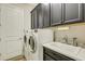 Laundry room with white washer and dryer, dark cabinetry, and a utility sink at 5341 Greenbrook Dr, Sarasota, FL 34238