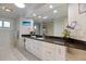 Bright bathroom featuring a large mirror, granite countertop, white cabinets, and tile flooring at 121 Holly Ave, Sarasota, FL 34243