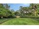 Landscaped front yard with lush greenery, mature trees, and a manicured lawn at 1423 Kimlira Ln, Sarasota, FL 34231