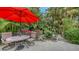 Relaxing patio with red umbrella, table, and chairs, surrounded by lush tropical foliage at 1423 Kimlira Ln, Sarasota, FL 34231