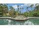 Serene pool with a rock waterfall feature and lush tropical landscaping at 1423 Kimlira Ln, Sarasota, FL 34231