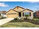 Tan house with brown garage door, landscaping, and a stone facade at 17741 Canopy Pl, Bradenton, FL 34211