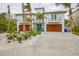 Two-story home with double wooden garage doors and landscaped front yard at 238 Oak Ave, Anna Maria, FL 34216