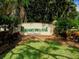 Community sign for Ravenwood, set amongst lush landscaping, flowers and green lawn at 3822 Ironwood Ct, Sarasota, FL 34243