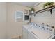 Well-lit laundry room includes a washer, dryer, storage shelf, and a window at 5713 Saint Louis Ave, Sarasota, FL 34233