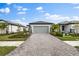 Single-story home with gray garage door and paver driveway, landscaping, and palm trees at 6240 Fish Eagle Ct, Nokomis, FL 34275