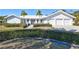 White house with a three-car garage and lush landscaping at 6851 Country Lakes Cir, Sarasota, FL 34243