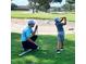 Golf lesson being taught on a beautiful green course with sand traps in the background at 6851 Country Lakes Cir, Sarasota, FL 34243