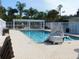 Inviting community pool area featuring lounge chairs, palm trees, and a pool lift for accessibility at 7619 Teal Trace, Bradenton, FL 34203