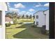 Scenic backyard view showcasing lush green grass, a serene pond, and towering palm trees under a beautiful blue sky at 796 Capri Isles Blvd # 242, Venice, FL 34292