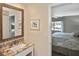 Bathroom showcasing a granite vanity and a decorative mirror, with a partial view into the bedroom at 796 Capri Isles Blvd # 242, Venice, FL 34292