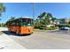 Orange and green trolley traveling on a road with palm trees at 9393 Midnight Pass Rd # 302, Sarasota, FL 34242