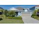 One-story home with blue siding, gray garage door, and landscaped yard at 10624 Falling Leaf Ct, Parrish, FL 34219