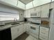 Bright kitchen with white cabinets, granite countertops, and modern appliances at 100 The Esplanade N # 6, Venice, FL 34285