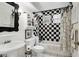 Black and white themed bathroom with checkerboard tiles, a pedestal sink, and a unique shower curtain at 115 Burns Rd, Terra Ceia, FL 34250