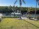 Waterfront view featuring a private boat dock, lush landscaping, and a boat under a clear sky at 115 Burns Rd, Terra Ceia, FL 34250