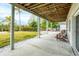 Inviting covered patio with exposed wood beams and view of the manicured backyard and mature palm trees at 115 Burns Rd, Terra Ceia, FL 34250