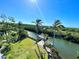 Waterfront property featuring a private dock and boat lift on a sunny day, surrounded by lush landscaping and swaying palm trees at 115 Burns Rd, Terra Ceia, FL 34250