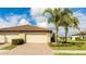 Two-car garage, tile roof, and landscaped yard with palm trees at 12563 Felice Dr, Venice, FL 34293