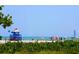 Scenic beach view with a lifeguard tower, beachgoers, and a sailboat on a sunny day at 1519 Harbor Dr, Sarasota, FL 34239