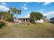 The back of the home features a yard with palm trees, desert-style landscaping, and a screen porch at 1716 Forest Rd, Venice, FL 34293