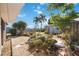 Backyard featuring an intricate garden, gravel beds, rock accents, lush trees, and a shed against a clear blue sky at 1716 Forest Rd, Venice, FL 34293