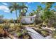 Backyard featuring a shed, palm trees, plants, flowers, and a wooden pathway leading to the shed at 1716 Forest Rd, Venice, FL 34293