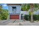 Contemporary two-story home featuring a modern facade, wood garage door, and tropical landscaping at 2434 Wood St, Sarasota, FL 34237