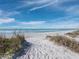 Sandy beach with dune grass, tire tracks and a blue sky background with wispy clouds at 415 L Ambiance Dr # C404, Longboat Key, FL 34228