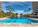 Long, beautiful community pool surrounded by palm trees and luxurious high-rise buildings at 415 L Ambiance Dr # C404, Longboat Key, FL 34228