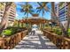 Open air pergola with a wooden walkway leading to a pool, framed by palm trees at 415 L Ambiance Dr # C404, Longboat Key, FL 34228