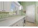 Bright laundry room with white cabinets, window, and green patterned wallpaper at 45 Grand Palms Blvd, Englewood, FL 34223