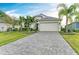 Single-story home with a paver driveway, landscaping, and palm trees at 4512 Renwick Dr, Parrish, FL 34219