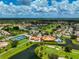 An aerial view featuring a tennis court, clubhouse, pool, and lush landscaping within the community at 4728 Sand Trap Street E Cir, Bradenton, FL 34203