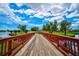 Scenic community bridge overlooking the golf course with lush landscaping and blue skies with dramatic clouds at 4728 Sand Trap Street E Cir, Bradenton, FL 34203