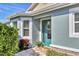 Inviting front entrance with teal door, stone accents, and lush landscaping at 5099 Flag St, Sarasota, FL 34232