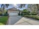 Exterior view of the home with a long driveway and brick accents at 7349 Windemere Ln, University Park, FL 34201