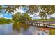 Scenic lake view with lush greenery and a wooden bridge at 7349 Windemere Ln, University Park, FL 34201