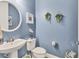 Powder room with pedestal sink, white toilet, and blue walls at 7876 Grande Shores Dr, Sarasota, FL 34240