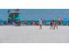 Vibrant beach scene with people enjoying the sun and sand, colorful umbrellas, and a lifeguard tower against a clear blue sky at 262 Island Cir, Sarasota, FL 34242