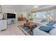 Cozy living room featuring comfortable seating, tile floors, and large window with a view of the landscaped yard at 309 South Dr, Nokomis, FL 34275