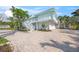 Charming two-story coastal home with a large brick driveway, lush tropical landscaping, and an attached garage at 3445 Anglin Dr, Sarasota, FL 34242