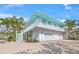Two-story coastal home featuring a balcony, lush tropical landscaping, an attached garage, and a brick driveway at 3445 Anglin Dr, Sarasota, FL 34242