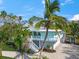 Beautiful light blue Key West home featuring a well-manicured lawn, lush tropical foliage, and a brick driveway at 3445 Anglin Dr, Sarasota, FL 34242