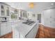 Bright kitchen with white cabinets, stainless steel appliances, a center island cooktop and lovely terra cotta tile floors at 3445 Anglin Dr, Sarasota, FL 34242