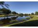 Scenic pond with green landscaping, trees, and clear blue sky reflecting in the water at 7254 Cedar Hollow Cir, Bradenton, FL 34203