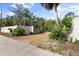 Shell driveway entrance framed by a short wall, mature trees, and shrubs at 7536 Midnight Pass Rd, Sarasota, FL 34242