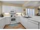 Bright kitchen with white cabinets, stainless steel appliances, and wood-look floors at 821 Evergreen Way, Longboat Key, FL 34228